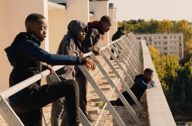 Les Misérables. Black boys stand on ledge, look out over city.