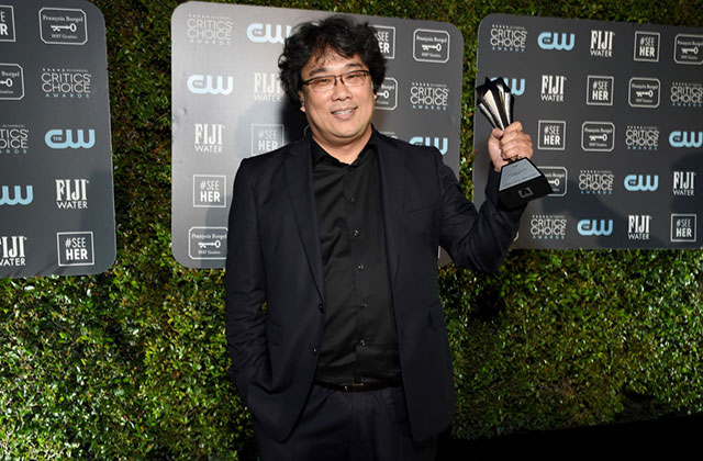 Bong Joon Ho. Korean man with dark hair wearing black jacket and shirt holding a Critics' Choice Award.