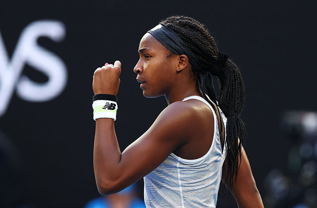 Coco Gauff. Young Black woman on tennis court wearing long braids, blue headband, white tank top and white and black wristband.