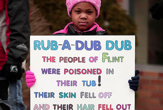 Young Black girl wearing a pink hat and matching pink coat holds a sign protesting the Flint water crisis in Flint, Michigan.