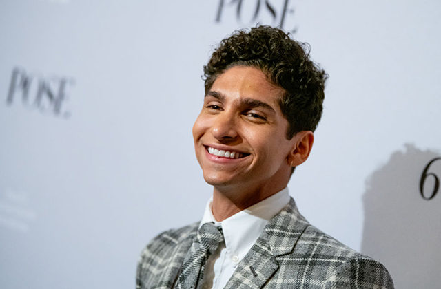 Angel Bismark Curiel. Latinx man, smiling, with short, dark curly hair wearing plaid tie and suit jacket with white shirt.
