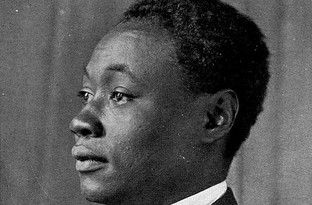 Claude McKay. Archival black and white photo of side profile of Black man wearing a white shirt and dark suit jacket.