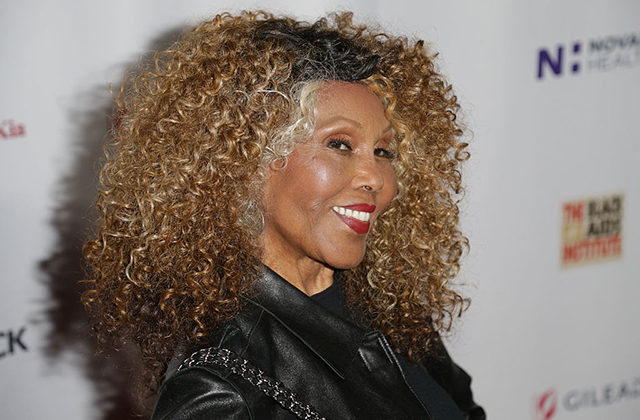 Ja’Net DuBois. Older Black woman, smiling, with long curly blonde hair wearing black top.