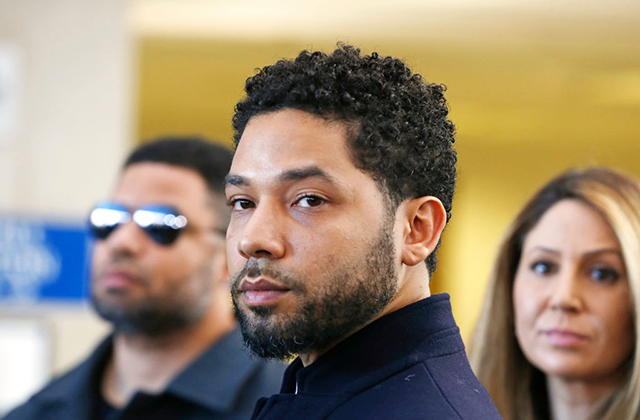 Jussie Smollett. Black man with short mustache and beard and short dark curly hair wearing dark suit jacket.