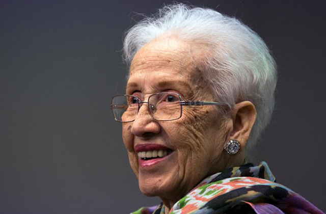 KATHERINE JOHNSON. Elder Black woman with short white hair, wearing glasses and a colorful top.