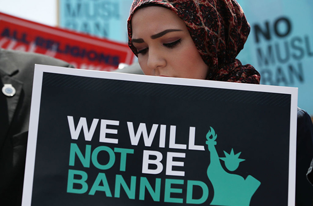 Muslim Ban. Muslim woman wearing brown headscarf and carrying a sign reading "We will not be banned"
