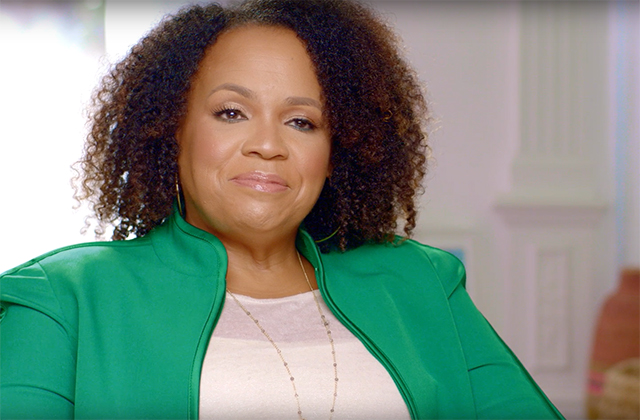 Lisa Price. Black woman with brown shoulder length curly hair wearing white top and green jacket.