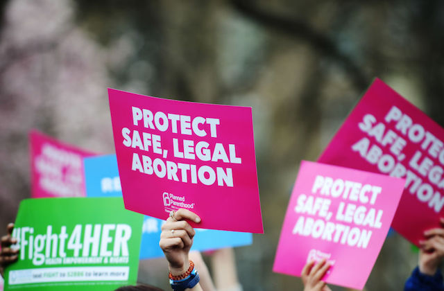 pink and green placard signs held in the air in support of abortion rights