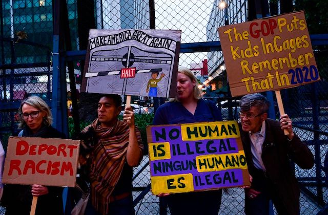 protesters hold signs calling for an end to detaining immigrants