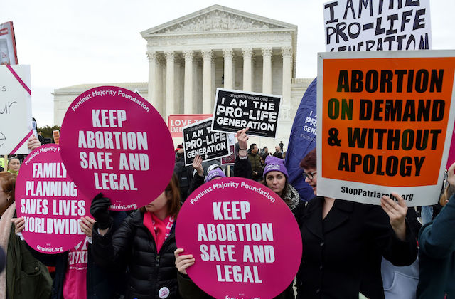 Protesters hold both pro-choice and anti-abortion signs in front of the U.S. Supreme Court.
