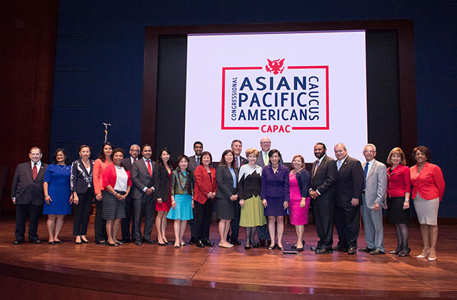 Congressional Asian Pacific American Caucus. Group of congressional employees standing on a stage in front of a blue curtain and sign reading  Congressional Asian Pacific American Caucus.