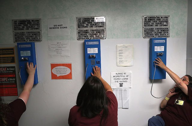 women with their backs to the camera can be seen dialing numbers on blue pay phones from prison.