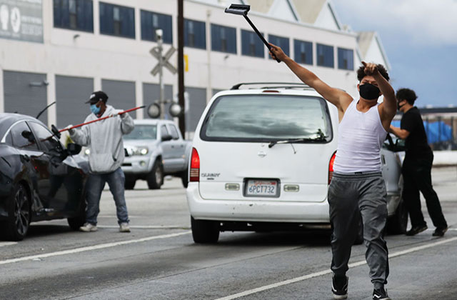Los Angeles COVD-19. Three men wearing face masks on a highway using squeegees to clean car windows.