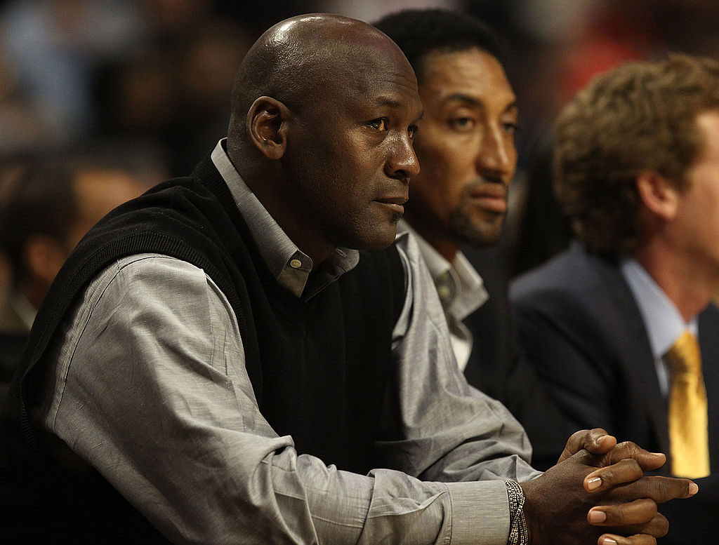 Michael-Jordan and Scottie Pippen. Black man with bald head wearing black vest and gray shirt sitting next to black man with short black hair.