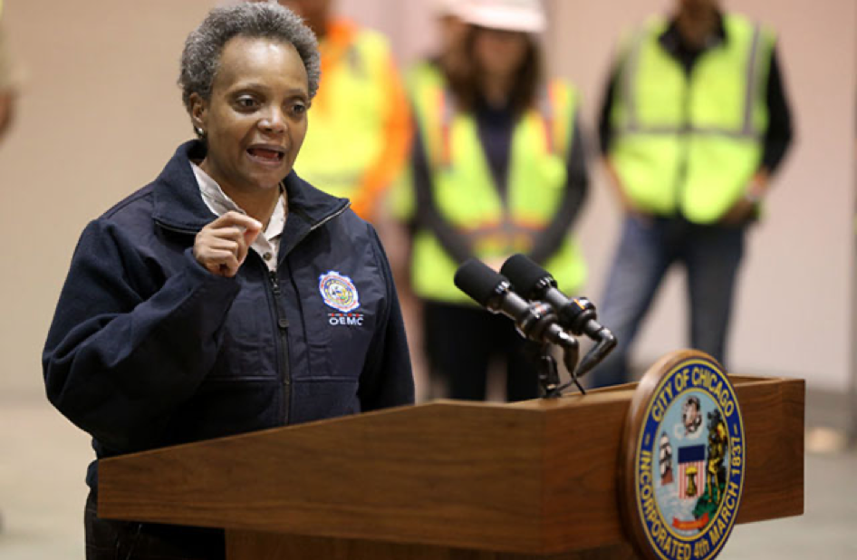 Chicago Mayor Lori Lightfoot. Brown-skinned Black woman with short salt and pepper hair, dressed in a blue windbreaker jacket