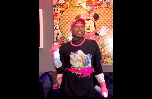 Todrick Hall. Black man wearing black top and pants with a pink cap and pink necklace.