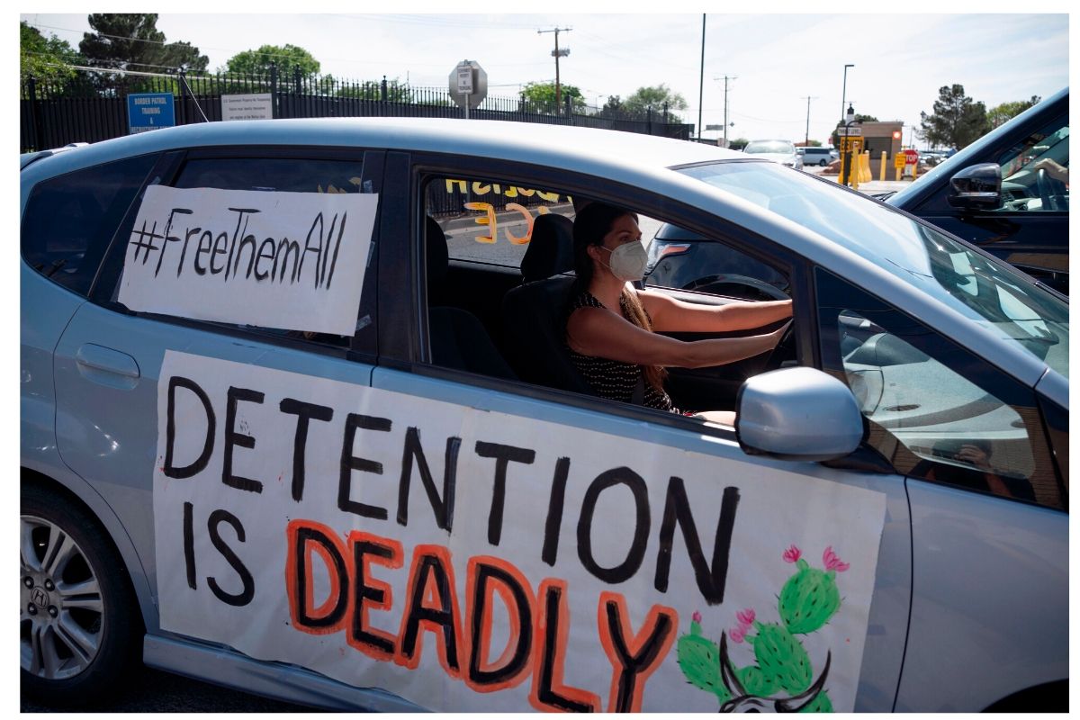 Protest against Detention. Woman in car with two signs reading "Detention is Deadly" and "Free Them All"