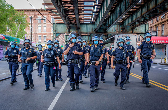NYPD-2020. A mob of uniformed officers walking under an elevated train.