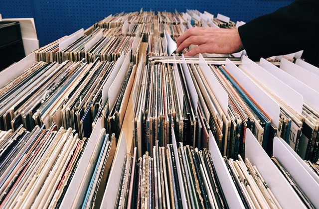 Records. Hand sifting through rows of vinyl records.