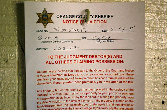 A paper eviction notice from the Orange Country Sheriff hanging on a door.