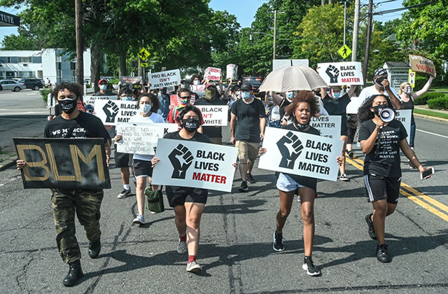 BLM Protestors. Multiracial group of young people carrying signs reading "Black Lives Matter."