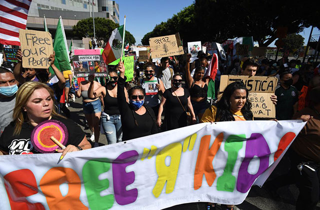 Free the Kids rally. Group of marchers hold colorful sign reading "Free R Kids."