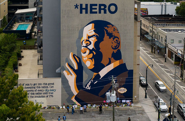 John Lewis mural. Mural of Black man with bald head wearing a suit with the words HERO above his head.