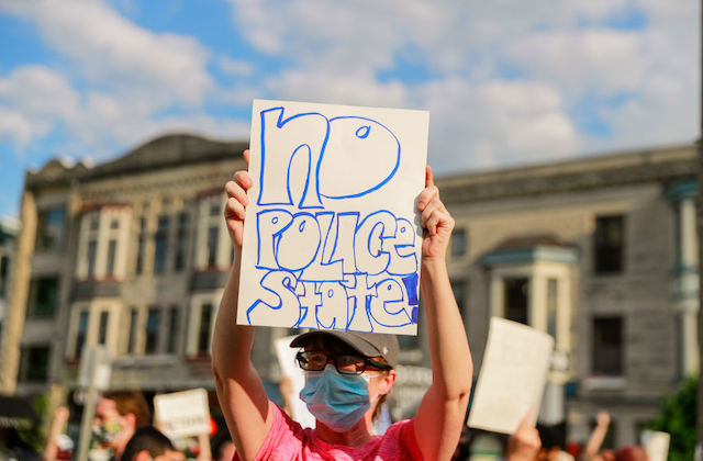 protester holds sign that reads, "no police state"