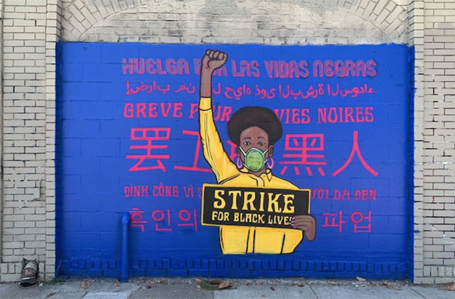 Brian-Herrera's art. Mural showing Black girl with black Afro wearing yellow and raising a fist.