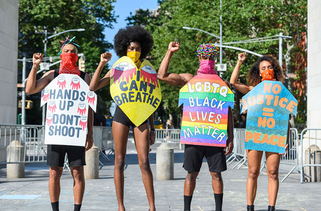 Protest ARt. Four models of color stand side-by-side wearing colorful body placards with BLM slogans.