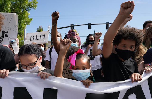 Young Black protesters hold their fists in the air during a Black Lives Matter march on August 1, 2020, in Portland, Oregon.