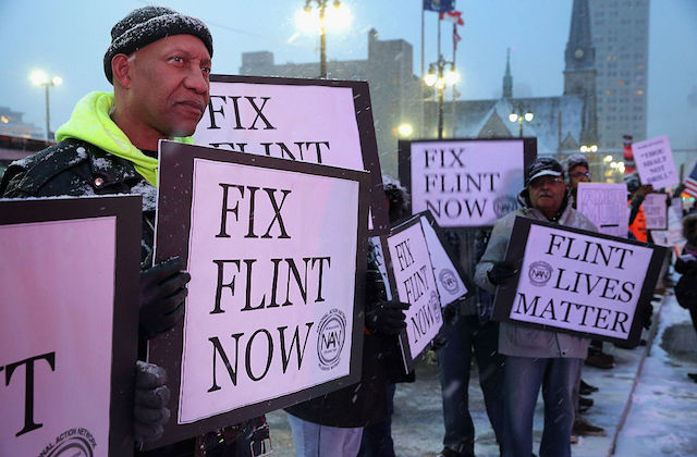 Protesters hold signs that read, Fix Flint Now and Flint Lives Matter