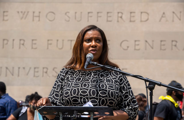 Black woman stands at a podium in front of a crowd and speaks into a microphone.