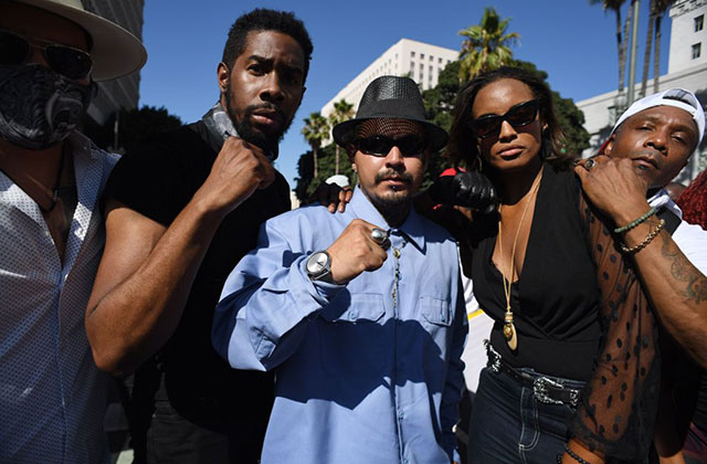 Antiracism-March. Five people, four men and one woman, pose outdoors with fists.