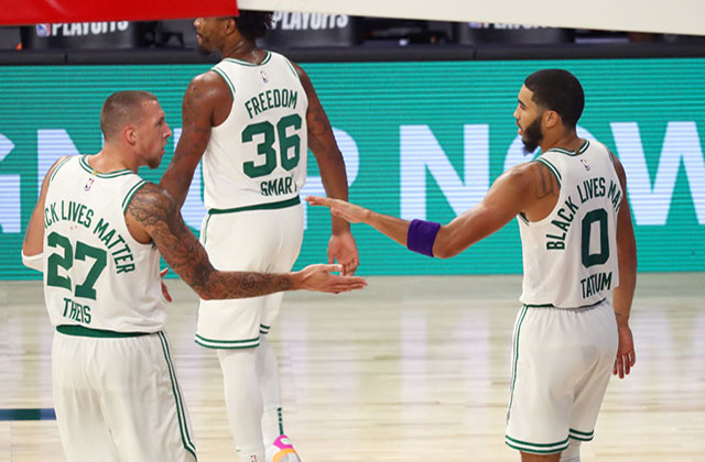 Boston Celtics-Three basketball players wearing white jerseys with green lettering walking away from the camera on court.