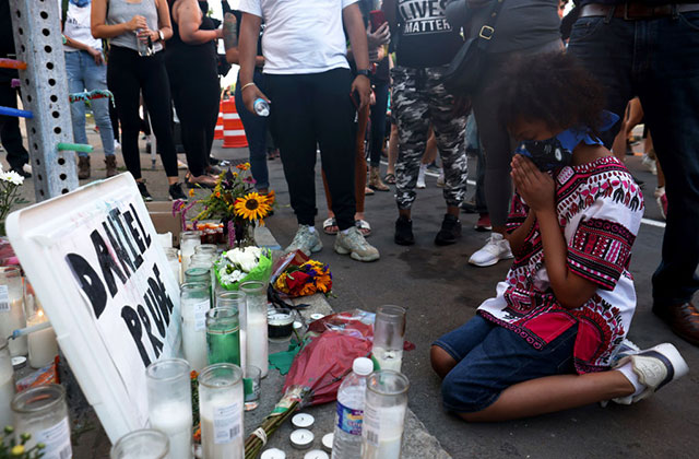 Daniel Prude. Young Black boy prayers on his knees on the ground at a makeshift memorial for Daniel Prude.