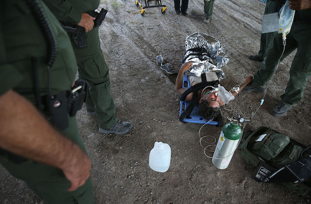a person lies on a blue mat and is covered in silver foil as they receive an IV treatment.