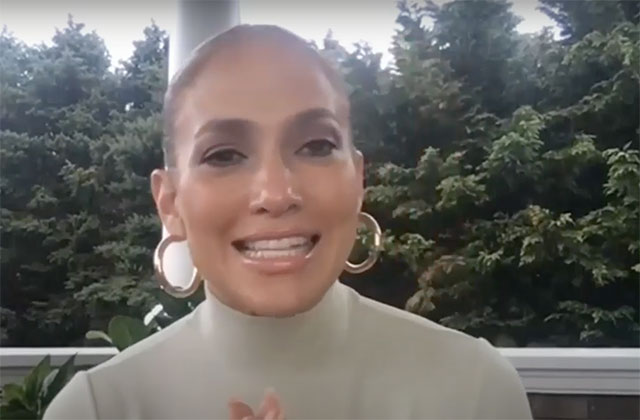 Jennifer Lopez. Latinx woman with hair pulled back wearing a taupe colored mock neck shirt on a balcony.