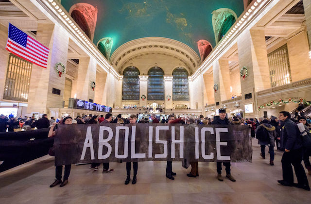 protesters hold a sign that reads, Abolish ICE