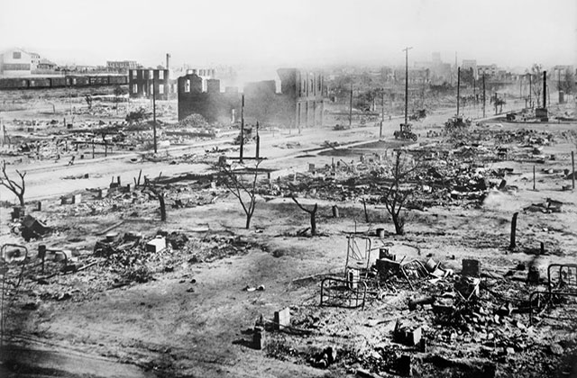 Tulsa. Black and white archival image of a burned down city of destroyed buildings and trees.
