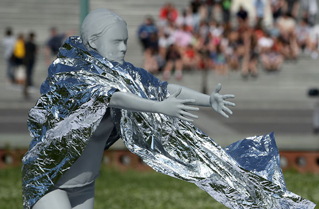 Child separation. A woman mannequin wearing a foil blanket reaches out with both hands.