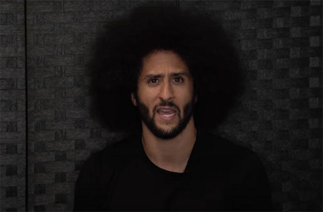 Colin Kaepernick. Black man with large dark Afro wearing a dark T shirt.