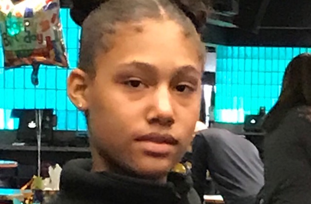 CLose-up of Black teen girl wearing two buns in her hair and gold stud earrings in her ears.