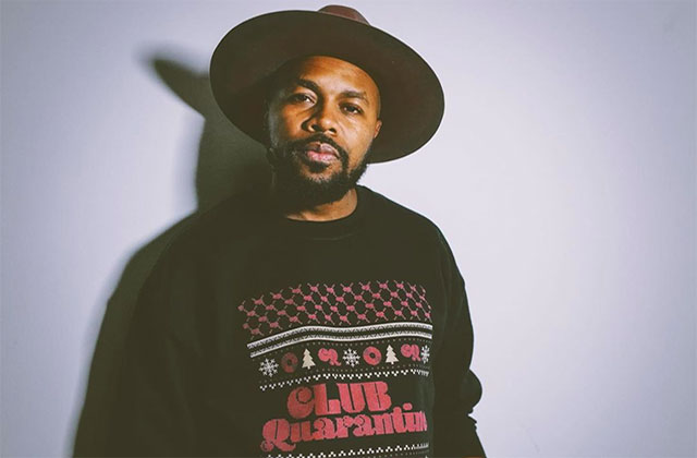 D-Nice. Black man wearing large-brimmed brown hat wearing a black sweatshirt reading "Club Quarantine."