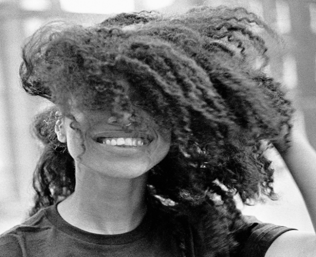 Lianne La Havas album cover displays a Black and white image of Lianne La Havas smiling with one hand in her natural hair which is covering half of her face.