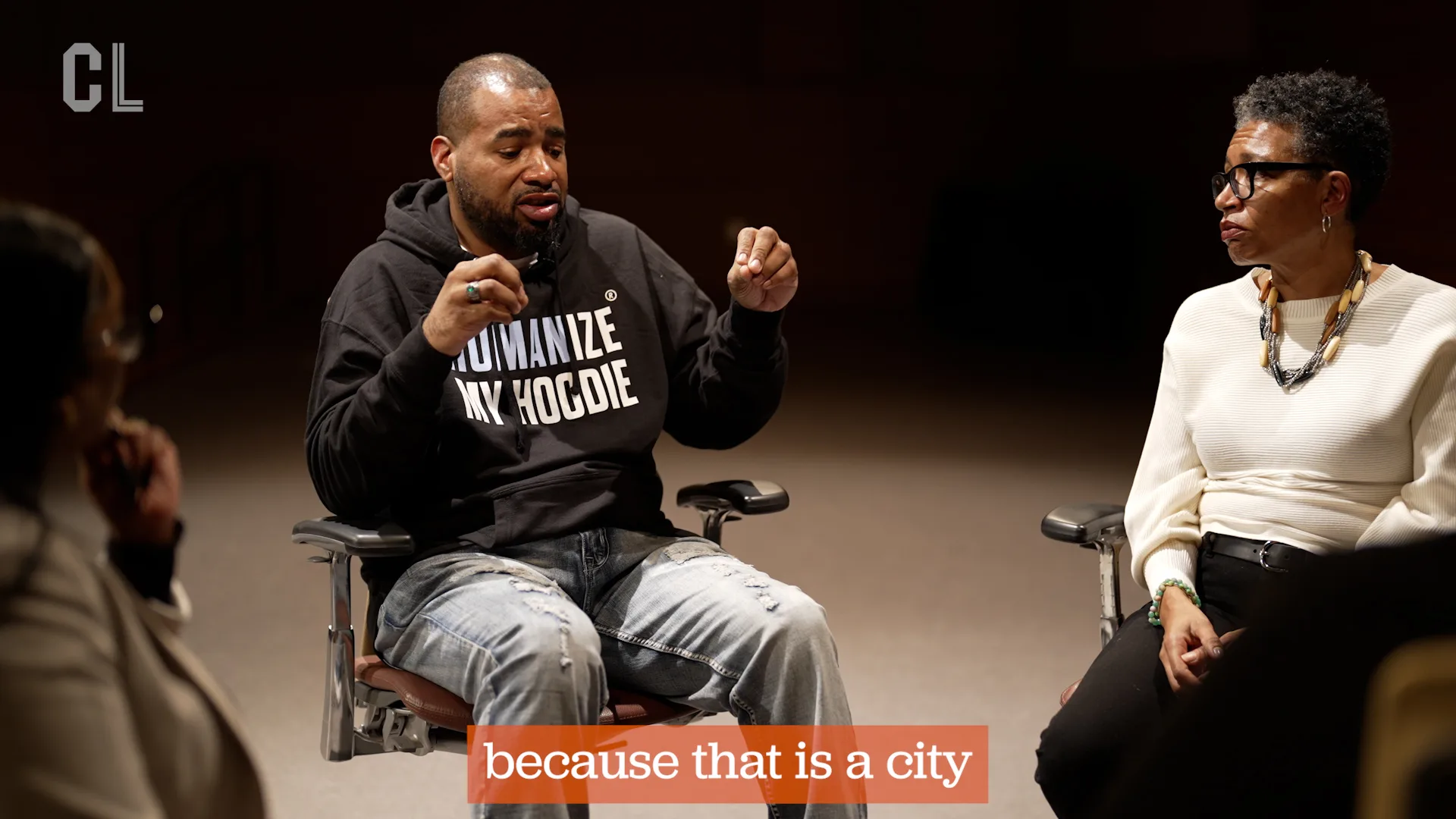One seated person looking at a second seated person talking with hand gestures