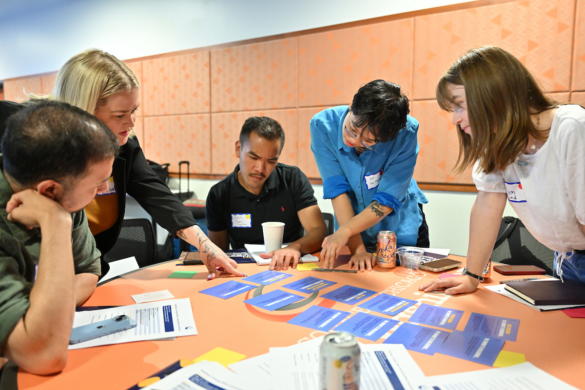 group of people around a table looking at blue flash cards. 