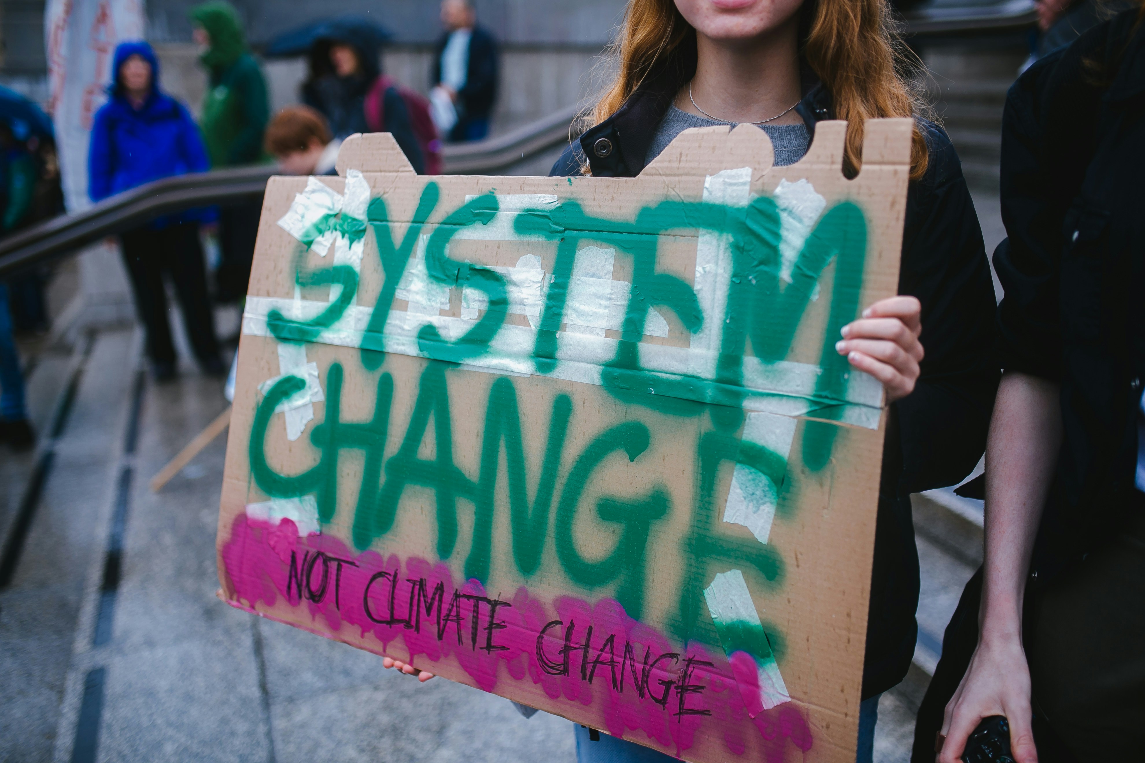 A girl holding a cardboard sign that says "System Change not Climate Change