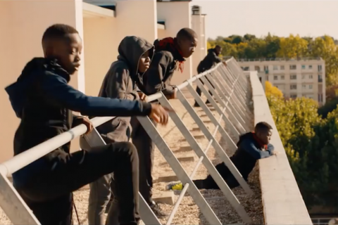 Les Misérables. Black boys stand on ledge, look out over city.
