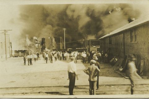 1921 Tulsa Massacre. Archival photo of people standing and looking at smoke rising.